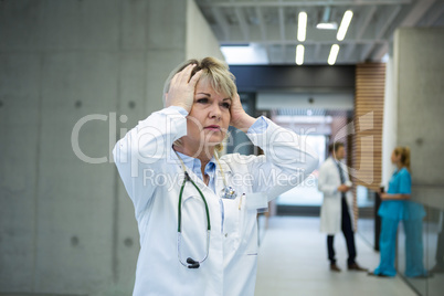 Thoughtful female doctor standing n corridor