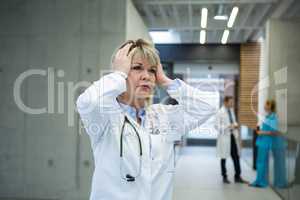 Thoughtful female doctor standing n corridor