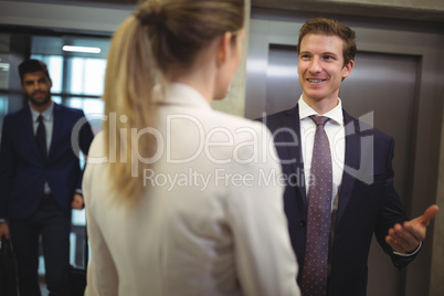 Businessman interacting with his female colleague near elevator