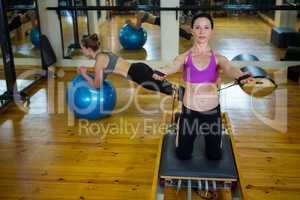 Portrait of happy woman practicing stretching exercise on reformer