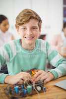Portrait of smiling schoolboy working on electronic project