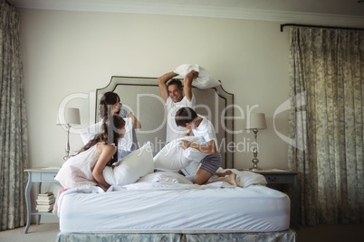 Parents and kids having pillow fight on bed