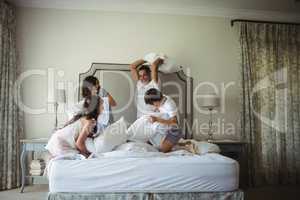 Parents and kids having pillow fight on bed