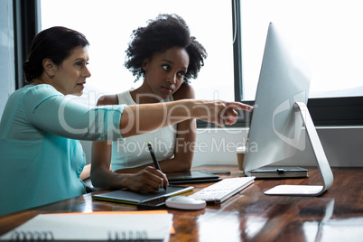 Female graphic designer pointing to desktop pc