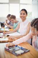 Portrait of smiling schoolgirl doing homework in classroom