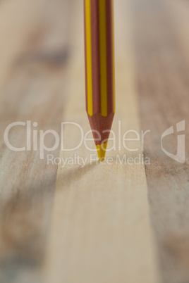 Yellow colored pencil on wooden background