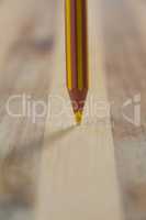 Yellow colored pencil on wooden background