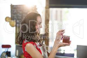 Female shop assistant looking a jar of jam