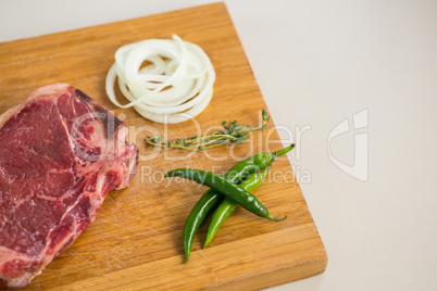 Sirloin chop, herbs and chillies on wooden tray