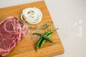 Sirloin chop, herbs and chillies on wooden tray