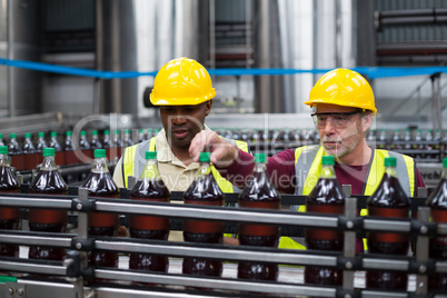 Factory workers monitoring drinks production line