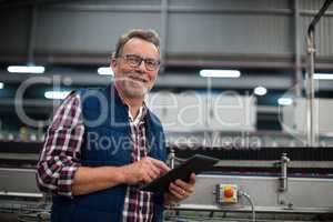 Smiling factory worker using digital tablet in the factory