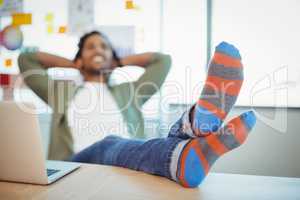 Male graphic designer relaxing with feet up at desk