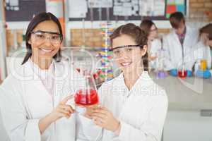 Smiling schoolgirls doing a chemical experiment in laboratory