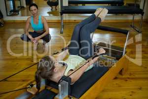Female trainer assisting woman with stretching exercise