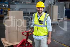 Factory worker pulling trolley of cardboard boxes in factory