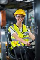 Portrait of smiling female factory worker driving forklift