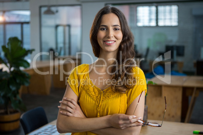 Female designer standing with arms crossed in creative office
