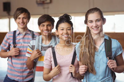 Portrait of happy students standing with schoolbags in campus