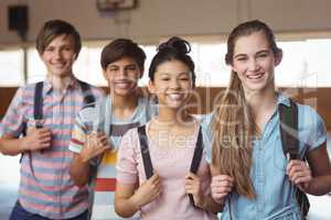 Portrait of happy students standing with schoolbags in campus