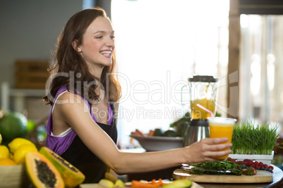 Smiling shop assistant offering the juice at the counter