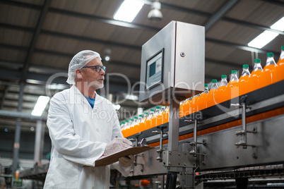 Factory engineer maintaining record on clipboard in factory