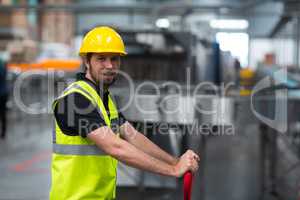 Smiling factory worker pulling trolley in factory