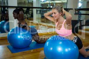 Two smiling women performing pilate on exercise ball