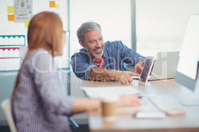 Male and female executive discussing over digital tablet