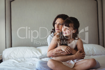 Mother embracing her daughter in bedroom
