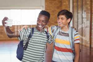 Happy schoolboys taking selfie on mobile phone in campus