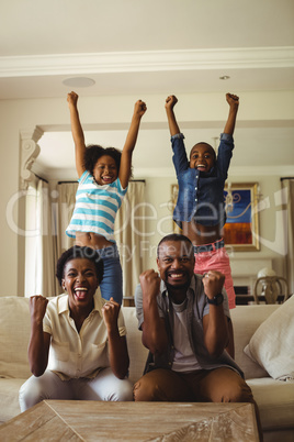 Parents and kids having fun while watching television in living room