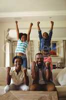 Parents and kids having fun while watching television in living room