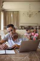 Portrait of man with laptop sitting in living room