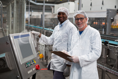 Two factory engineers standing near machine in factory