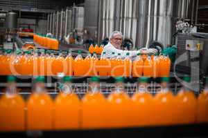 Factory engineer monitoring filled juice bottle on production line