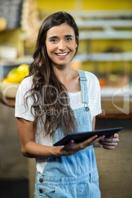 Smiling woman using digital tablet in the grocery store