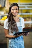Smiling woman using digital tablet in the grocery store
