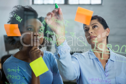 Female graphic designers writing on glass