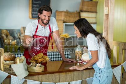 Bakery staff showing snack to the female customer at counter