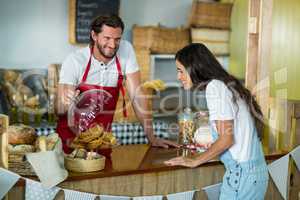 Bakery staff showing snack to the female customer at counter