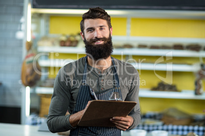 Portrait of salesman writing in clipboard at counter