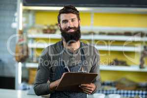 Portrait of salesman writing in clipboard at counter