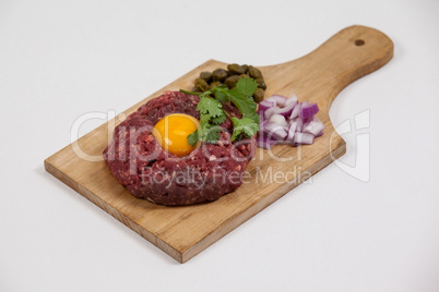 Beef patty, onions and olives on wooden board