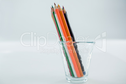 Colored pencils kept in glass on white background