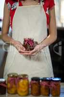 Female shop assistant holding a jar of jam