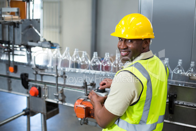 Smiling factory worker operating machine in factory