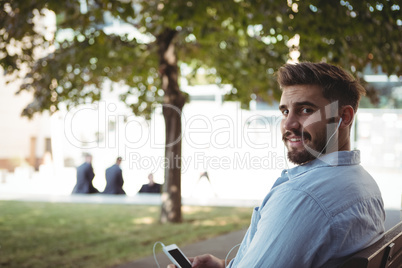 Executive listening music on mobile phone in park