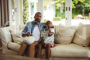 Father covering sons eyes while watching television