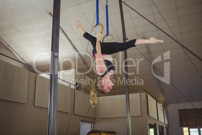 Female gymnast practicing gymnastics on rings